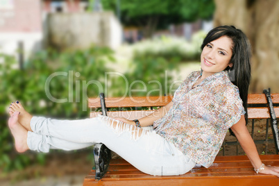 Portrait of smiling young girl sitting in bank in park