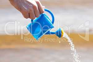 hand of a man with a watering can on a background of water