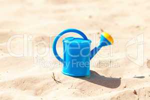 watering can on a background of sand