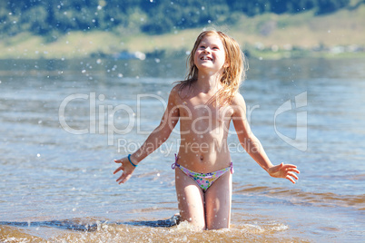 beautiful little girl splashes in the water