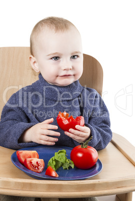 young child eating tomatoes in high chair