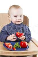 young child eating tomatoes in high chair