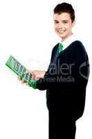 Charming smiling school kid operating calculator