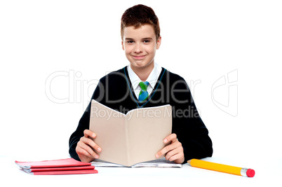 Cute school kid holding notebook and reading