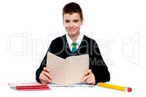 Cute school kid holding notebook and reading