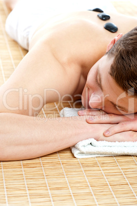 Man relaxing on carpet with hot stones