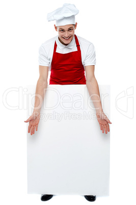 Handsome young cook showing blank billboard