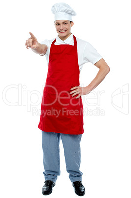 Male chef in uniform pointing away and smiling