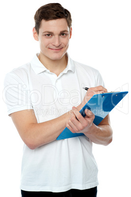 Smiling young man writing on notepad