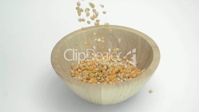 Corn kernels in super slow motion falling in a wooden bowl