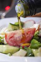 Olivenöl über Salat giessen