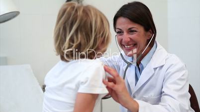 Smiling doctor auscultating a child