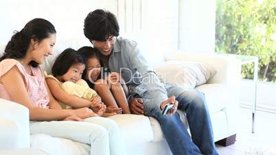 Family sitting on a sofa while looking at a camera