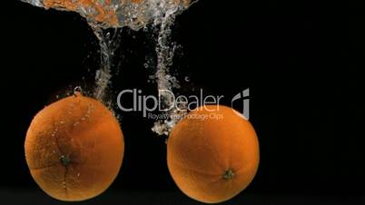Oranges falling in super slow motion into water