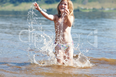 beautiful little girl splashes in the water