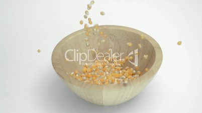Corn kernels in super slow motion falling in a bowl