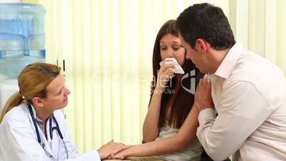 Doctor talking to a crying woman in a waiting room