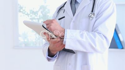 Smiling doctor writing on a clipboard