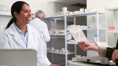 Smiling pharmacist handing paper to a customer
