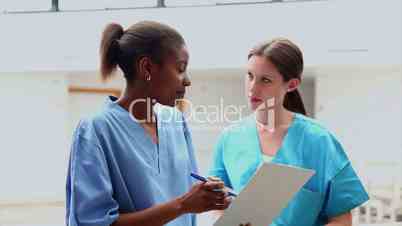 Female nurse and intern holding a clipboard