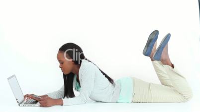 Woman lying on the floor while typing on a laptop