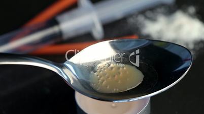 Heroin in a silver spoon being heated by a tea light