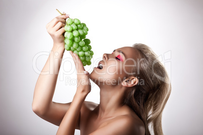 Pretty young woman eat green grapes