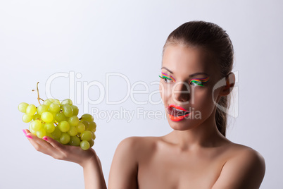 Funny woman with glow make-up and green grapes