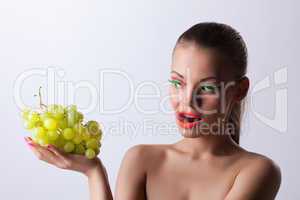 Funny woman with glow make-up and green grapes