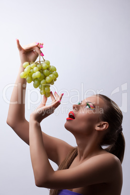 Pretty young woman eat green grapes