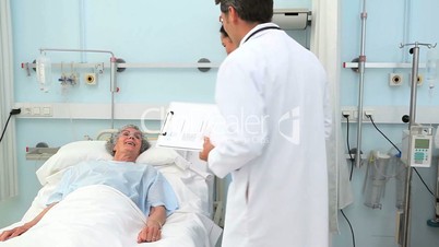Doctor and nurse looking at camera next to a patient lying