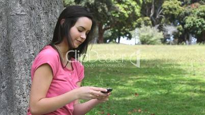 Smiling woman using a mobile phone in a park