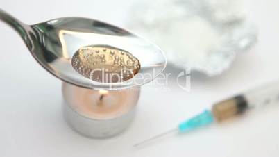 Heroin in a spoon with a syringe being heated by a tea light