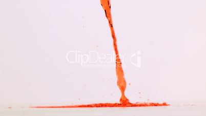 Orange liquid flowing in super slow motion on a ground