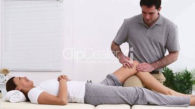 Physiotherapist massaging the knee of one on his patient