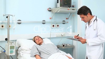Doctor writing on his clipboard next to his patient