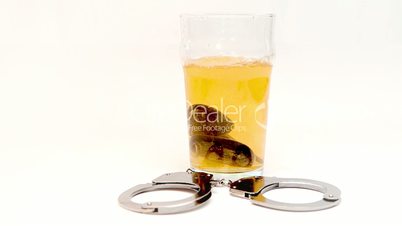 Car keys falling in a glass full of beer surrounded by cuff