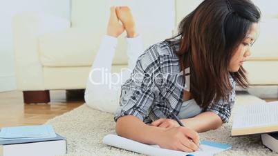 Woman studying while lying on the flloor