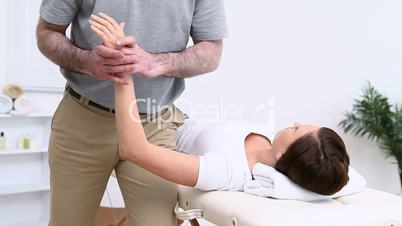 Physiotherapist stretching the arm of a woman