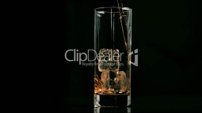 Fizzy drink poured in super slow motion in a glass with ice