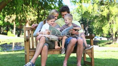 Family sitting on a bench reading a book