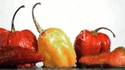 Peppers in super slow motion being placed next to chilies