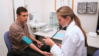 Smiling doctor measuring the blood pressure of his patient