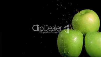 Three apples being watered in super slow motion