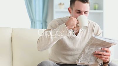 Casual man drinking a coffee while reading the news