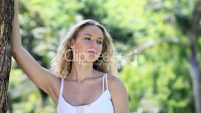 Smiling woman leaning on a tree