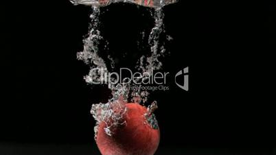 Red apple diving in super slow motion into water