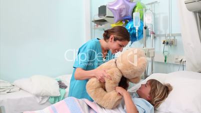 Smiling nurse showing a teddy bear to a child