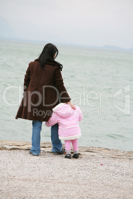 Mother and daughter looking the sea on winter