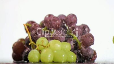 Colorful grapes in super slow motion receiving drops